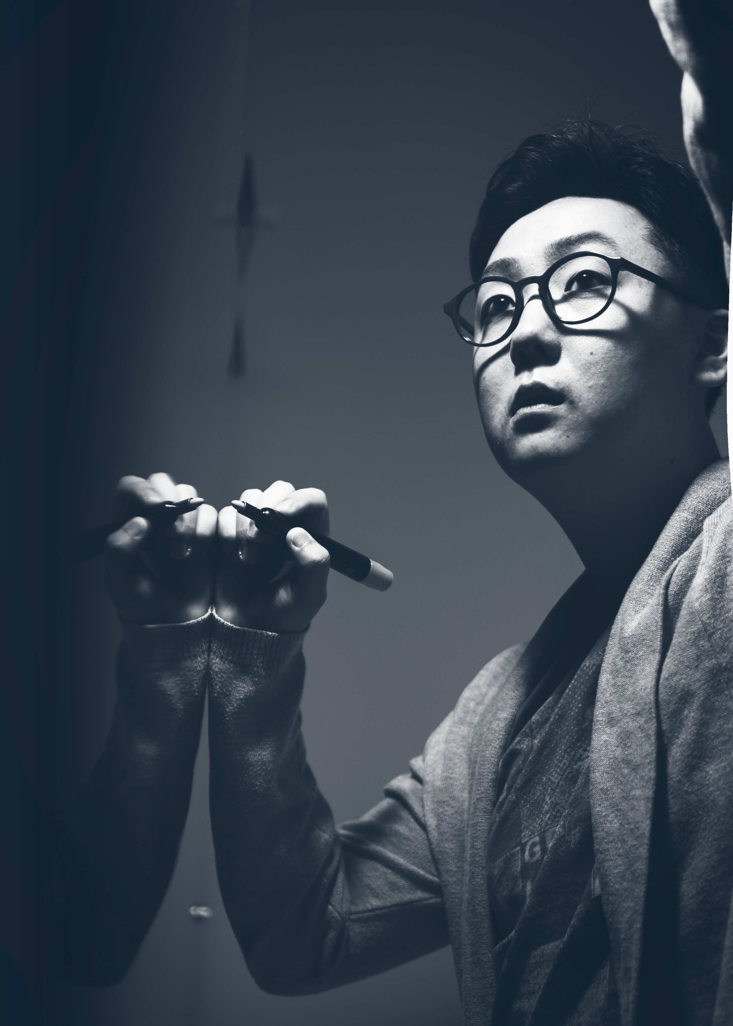 John Taesup Kim holding a marker beside reflective glass